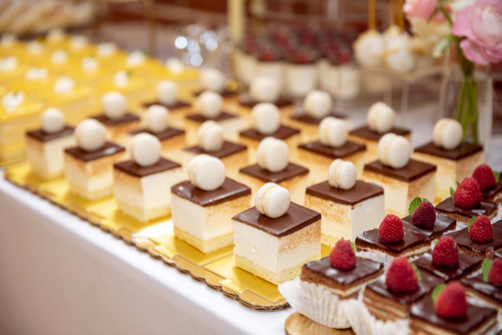 A lavish dessert table featuring a variety of pastries including chocolate tarts and layered cakes.